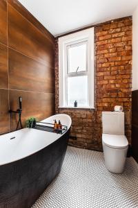 a bathroom with a white tub and a brick wall at The Crescent Townhouse in Lisburn