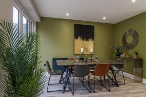uma sala de jantar com paredes verdes e uma mesa e cadeiras em Festival Villa and City Villa em Edimburgo