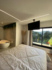 1 dormitorio con cama, bañera y ventana en Lindo Apartamento com banheira e linda vista a 500 m do Capivari, en Campos do Jordão
