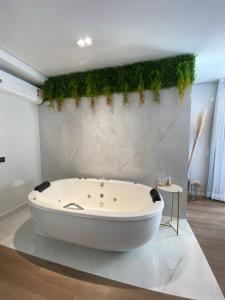 bañera blanca con plantas en la pared en Lindo Apartamento com banheira e linda vista a 500 m do Capivari, en Campos do Jordão