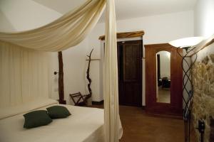 a bedroom with a canopy bed with green pillows at Nascar Hotel in Santa Maria Navarrese