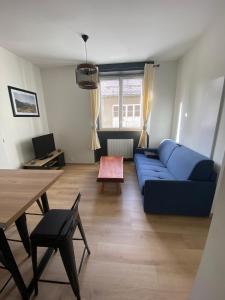 sala de estar con sofá azul y mesa en Le Côté Cour en Barcelonnette