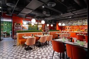 a restaurant with tables and chairs and red walls at Hyatt Place London City East in London