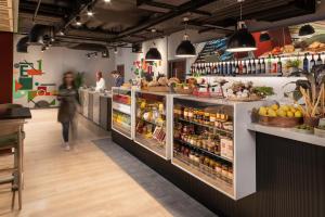 a woman walking through a grocery store with a display of food at Hyatt Place London City East in London