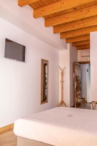 1 dormitorio con cama blanca y techo de madera en ANJ Alojamientos, en Guadalupe