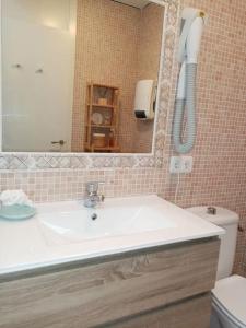 La salle de bains est pourvue d'un lavabo, d'un miroir et de toilettes. dans l'établissement Precioso apartamento en complejo con piscina, à Cala'n Bosch
