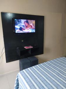 a flat screen tv on a wall in a bedroom at Suítes econômica 250 metros do mar in Piçarras