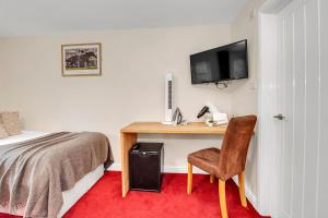 um quarto com uma secretária, uma cama e uma cadeira em The Cambridgeshire em Newmarket