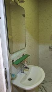 a bathroom sink with a mirror and a green shelf at Gold Baku in Baku