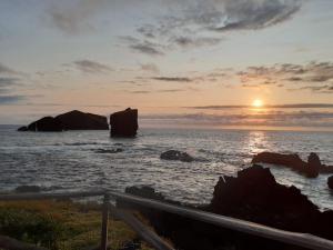 a sunset over the ocean with rocks in the water at Casa da Ribeira - Mosteiros in Mosteiros