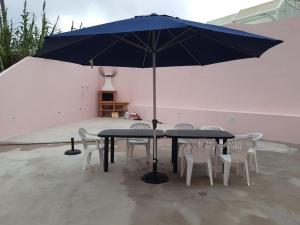 a table and chairs with a blue umbrella at Casa da Ribeira - Mosteiros in Mosteiros