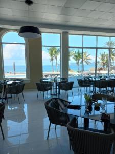 een eetkamer met tafels en stoelen en het strand bij Hacienda Mazatlán sea view in Mazatlán