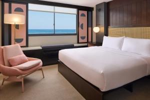 Hotel Renew في هونولولو: غرفة نوم بسرير وكرسي ونافذة