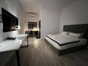 Dormitorio con cama, escritorio y TV en Macchiato Resort Savannakhet Opposite Thai Embassy en Savannakhet