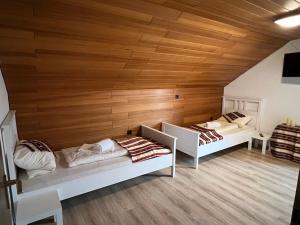 two beds in a room with wooden walls at Gästehaus Schwabach in Schwabach