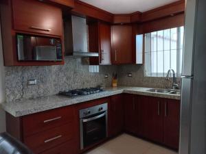 a kitchen with wooden cabinets and a stove top oven at Privacidad y comodidad in Los Mochis