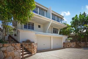 a large white house with two garage doors at 2 Casuarinas Peregian Beach in Coolum Beach