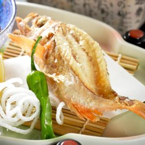 un trozo de pescado en un plato con fideos en Kyukamura Echizen-Mikuni en Sakai