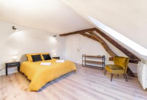 a bedroom with a large yellow bed and a chair at Au cœur de joigny in Joigny