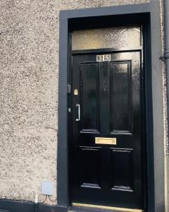 une porte noire avec son numéro dans l'établissement Heights View Apartment, à Derry Londonderry