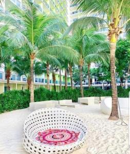 a white bench in a courtyard with palm trees at AZURE Urban Resort Residences Condominium in Manila