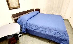 Bett mit blauer Decke in einem Zimmer in der Unterkunft Roxy Alto Belvedere in Casale la Cogna