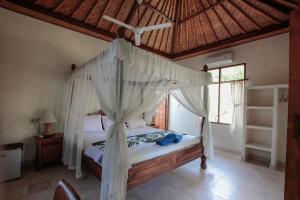 a bedroom with a canopy bed in a room at Ganesha Amed in Amed