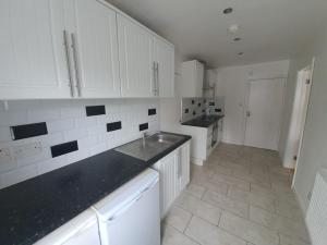 a kitchen with white cabinets and black counter tops at Chantilly in Ickenham +6 photos