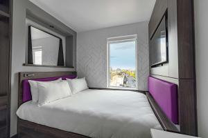 1 dormitorio con 1 cama grande y 2 ventanas en YOTEL London Shoreditch, en Londres