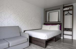 YOTEL London Shoreditch في لندن: غرفة نوم بسرير وكرسي ومرآة
