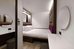 een kleine kamer met een bed en een spiegel bij YOTEL London Shoreditch in Londen