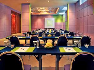 une salle de conférence avec des tables, des chaises et un écran dans l'établissement Ibis Styles Bali Denpasar, à Denpasar