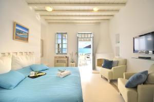 a bedroom with a blue bed and a couch at Mykonos Pantheon in Kalo Livadi