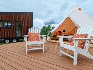 two chairs and a table on a deck with a tent at Glamping Vineyard Getaway with Luxury Amenities in Broke