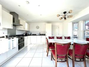 a kitchen with white cabinets and a table with red chairs at Lovely 4 doubled bedroomed townhouse in Bicester near to Bicester Village in Bicester