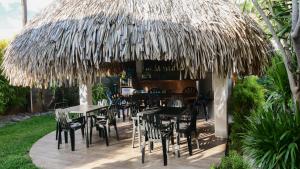 a restaurant with tables and chairs under a thatched roof at Pension De La Plage in Punaauia