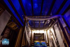 Cette chambre est dotée d'un plafond bleu et d'un lit. dans l'établissement Caraibes insolite, à Sainte-Luce