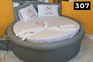 Cama en habitación con sábanas y almohadas blancas en Hotel l Motel 1001 Noites - Ceilândia, en Brasilia