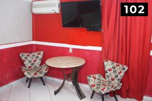 mesa y sillas en una habitación con TV en Hotel l Motel 1001 Noites - Ceilândia, en Brasilia