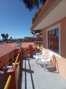 eine Terrasse mit weißen Stühlen und ein Gebäude in der Unterkunft Paqariy lodge in Ocosuyo