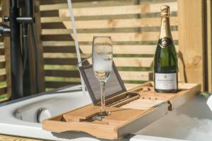 a bottle of champagne and a wine glass in a bath tub at The Trossachs Collection in Kepculloch