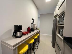 eine Küche mit einer Theke mit gelben Stühlen in der Unterkunft NU01- NOVO | 2 Quartos | Churrasqueira | Garagem in Balneário Camboriú