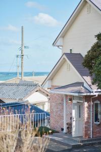 a brick house with a porch with the ocean in the background at ritomaru house iki ashibe in Iki
