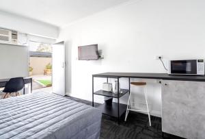 a bedroom with a bed and a kitchen with a microwave at City West Motel in Adelaide