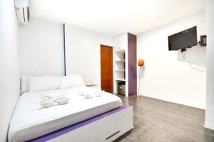 a white bedroom with a large bed and a tv at BABOSAM Hotel in Boracay