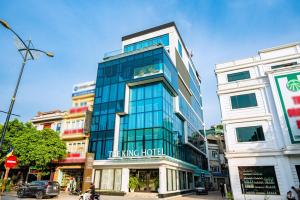 um edifício de vidro alto numa rua da cidade em The King Hotel - Condotel Thai Nguyen em Thái Nguyên