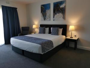 um quarto com uma cama grande e 2 candeeiros em The Abbey Motel Goulburn em Goulburn