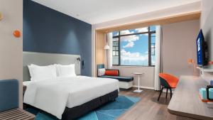 長沙的住宿－长沙大科城智选假日酒店，配有一张床和一张书桌的酒店客房