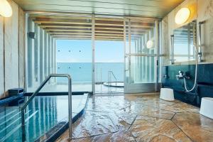 ein Bad mit einem Pool und Meerblick in der Unterkunft KAMENOI HOTEL Oarai in Oarai