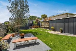 a backyard with a wooden bench and grass at Cape Surf House in Cape Woolamai